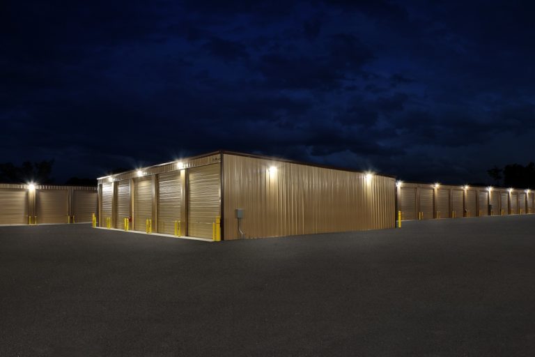 Large lit industrial storage warehouse complex with brown warehouse buildings at night